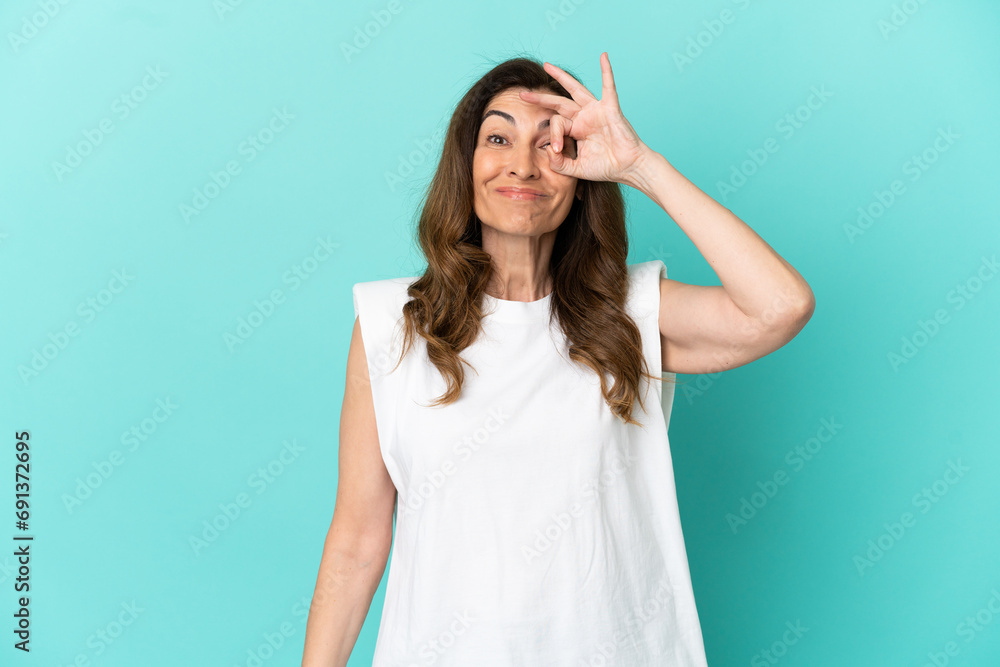 Middle aged caucasian woman isolated on blue background showing ok sign with fingers
