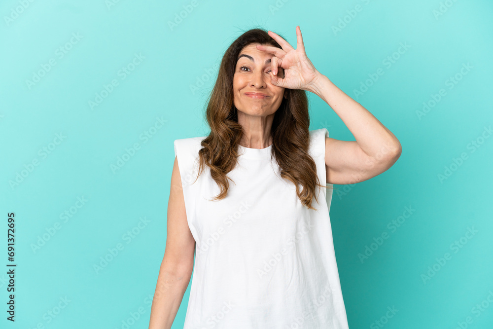 Middle aged caucasian woman isolated on blue background showing ok sign with fingers Middle aged caucasian woman isolated on blue background showing ok sign with fingers