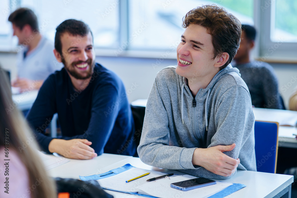© Westend61 - Smiling multi-ethnic friends sitting at desk in ed training class © Westend61 - Smiling multi-ethnic friends sitting at desk in ed training class