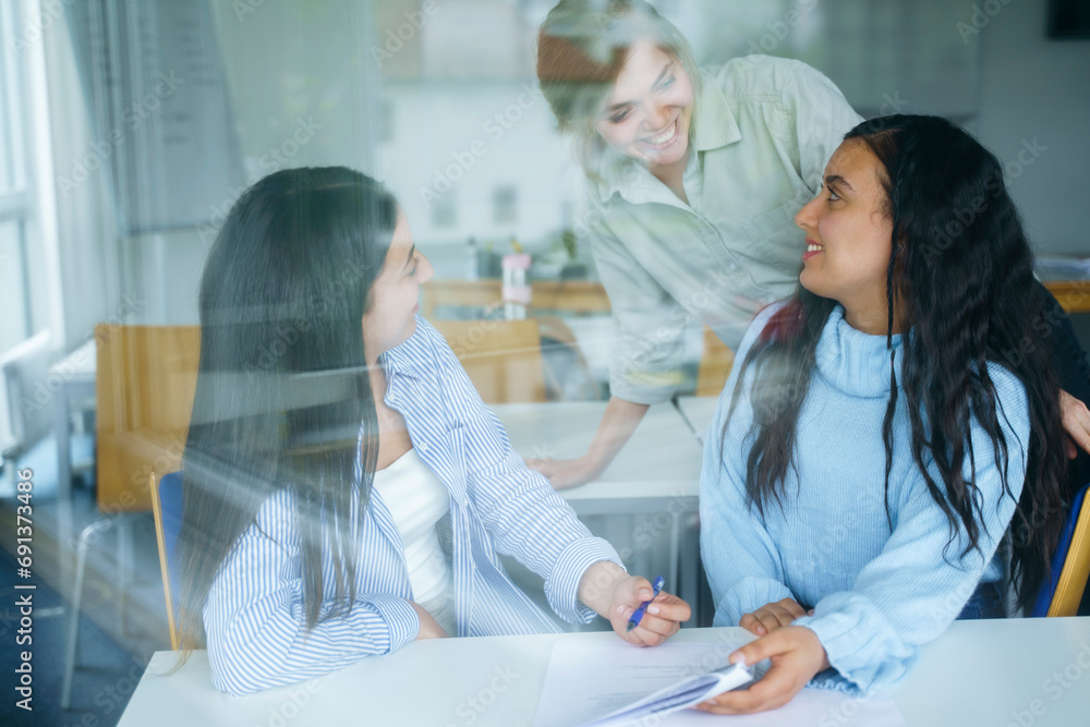 Smiling multi-ethnic students seen through glass in classroom Smiling multi-ethnic students seen through glass in classroom