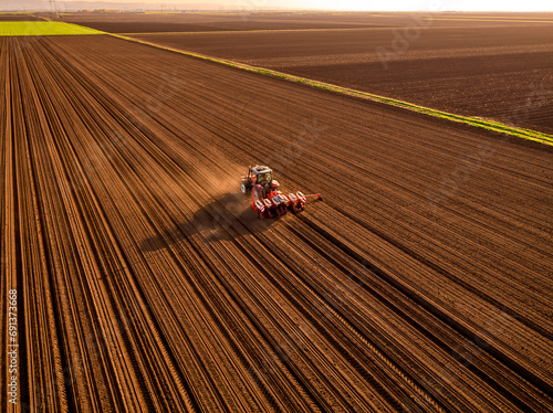 Serbia, Vojvodina Province, Aerial view of tractor sowing seeds in plowed corn field photo