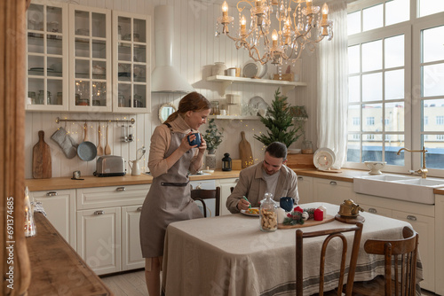 Man decorating cookies with woman standing at table in kitchen photo