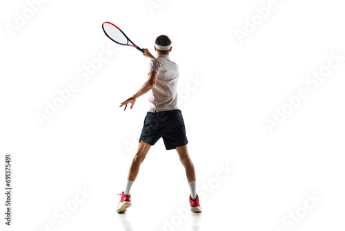 Back view image of young man in motion with racket, tennis player during game, training isolated over white background. Concept of sport, hobby, active and healthy lifestyle, competition © master1305