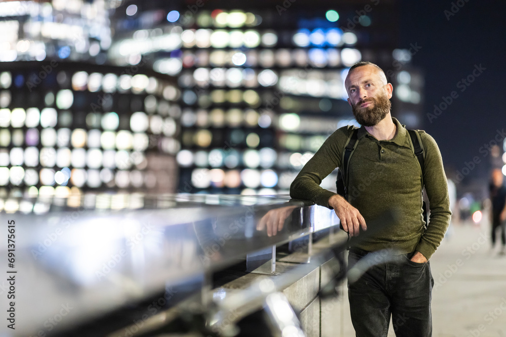 Man with hand in pocket leaning on railing in city Man with hand in pocket leaning on railing in city