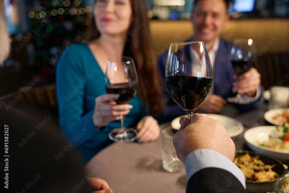 Happy people holding a glasses of wine while celebrating Christmas Happy people holding a glasses of wine while celebrating Christmas