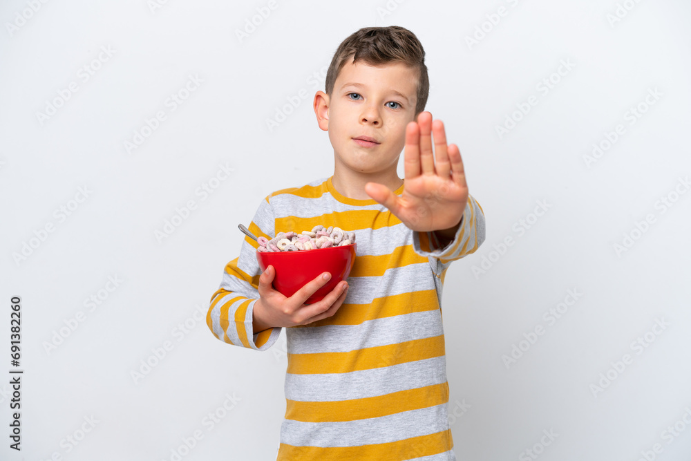 Little caucasian boy holding a cereal bowl isolated on white background making stop gesture Little caucasian boy holding a cereal bowl isolated on white background making stop gesture