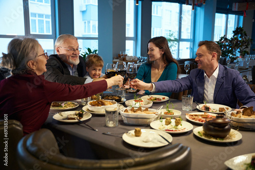 Family holding glasses with wine while celebrating Christmas in the restaurant