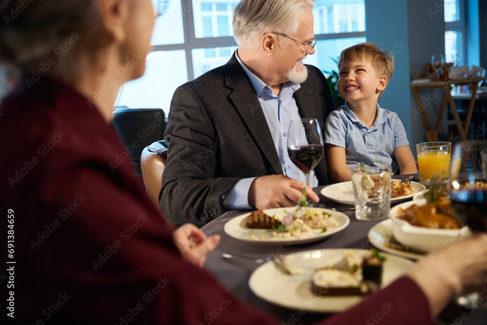 Happy old man and little boy looking at each other in the restaurant Happy old man and little boy looking at each other in the restaurant