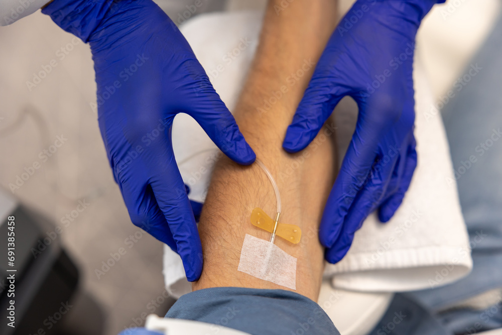 Obraz premium Inserting catheter into vein in patient's arm in hospital medicinal solution intravenously.