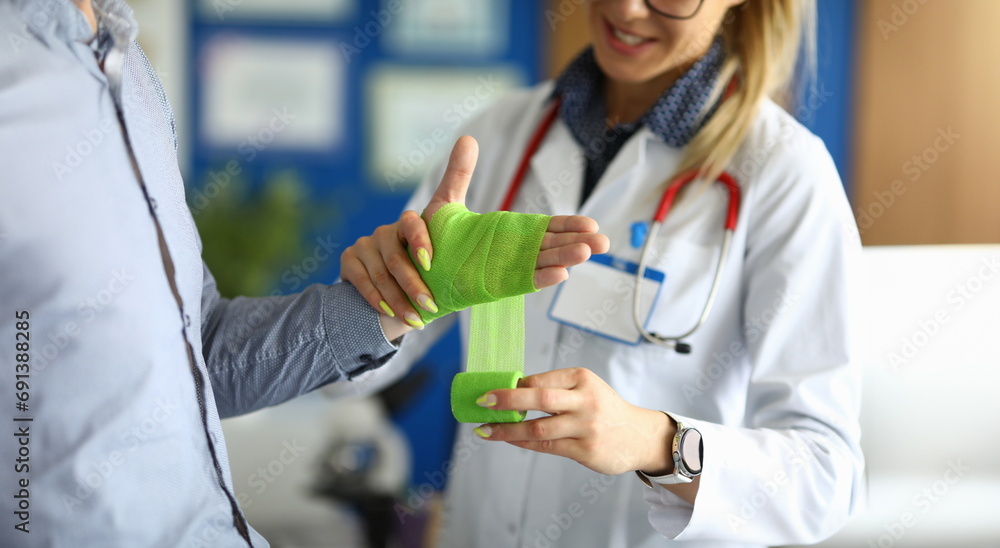 First aid and treatment for injuries and disorders of wrist. Traumatologist takes care of patient and female doctor bandages hand concept First aid and treatment for injuries and disorders of wrist. Traumatologist takes care of patient and female doctor bandages hand concept