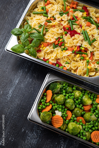 Containers with pasta and vegetables in the kitchen