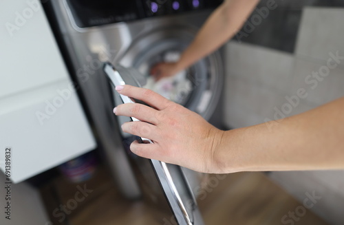 Woman hand fills drum of washing machine. Household chores and turning on washing machine concept