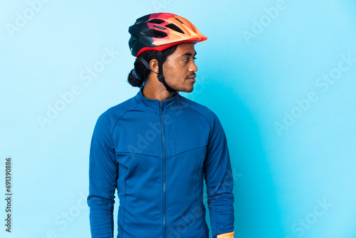 Young cyclist man with braids over isolated background looking to the side © luismolinero