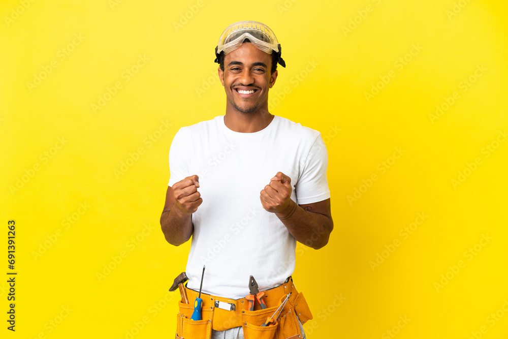 African American electrician man over isolated yellow wall celebrating a victory in winner position