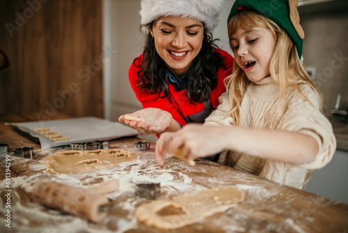 Mother and child daughter girl are cooking cookies and having fun in the kitchen. Homemade food and little helper.