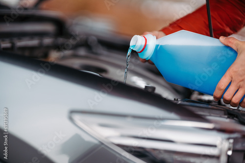 Pouring winter washer fluid into car reservoir during winter, protecting it from freezing. photo