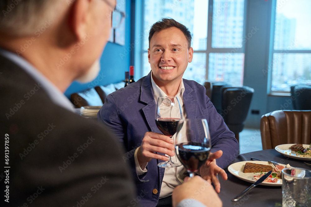 Man in restaurant with unrecognizable male enjoying Christmas celebration