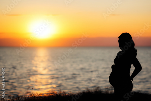 silhouette of a pregnant woman on the beach at sunset