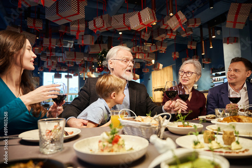 Aged man with glass of wine toasting greeting his family with Christmas holiday