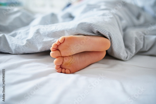 Little child's feet in bed covered with blanket © Ekaterina Pokrovsky