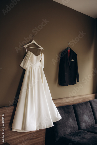 Bride and groom dresses hangs on the wall in the hotel photo