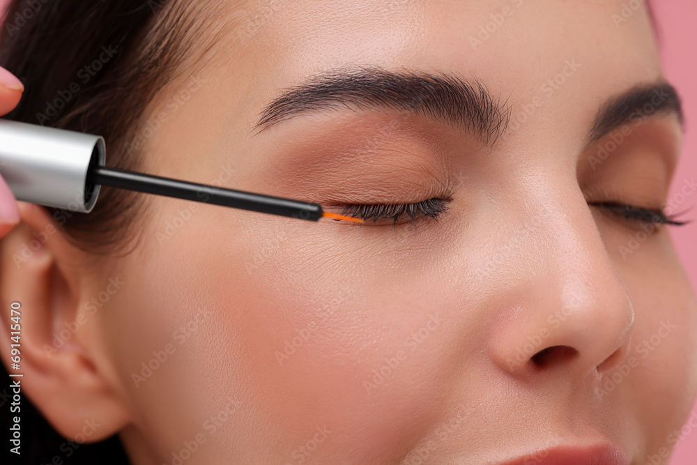 Woman applying serum onto her eyelashes, closeup. Cosmetic product