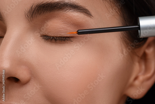 Woman applying serum onto her eyelashes, closeup. Cosmetic product