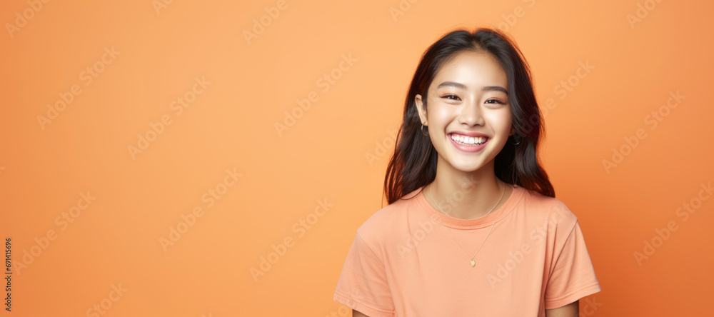 Obraz premium A pretty Asian woman, blending Malaysian and American features, showcases trendy fashion in a cheerful portrait with a yellow sweater.