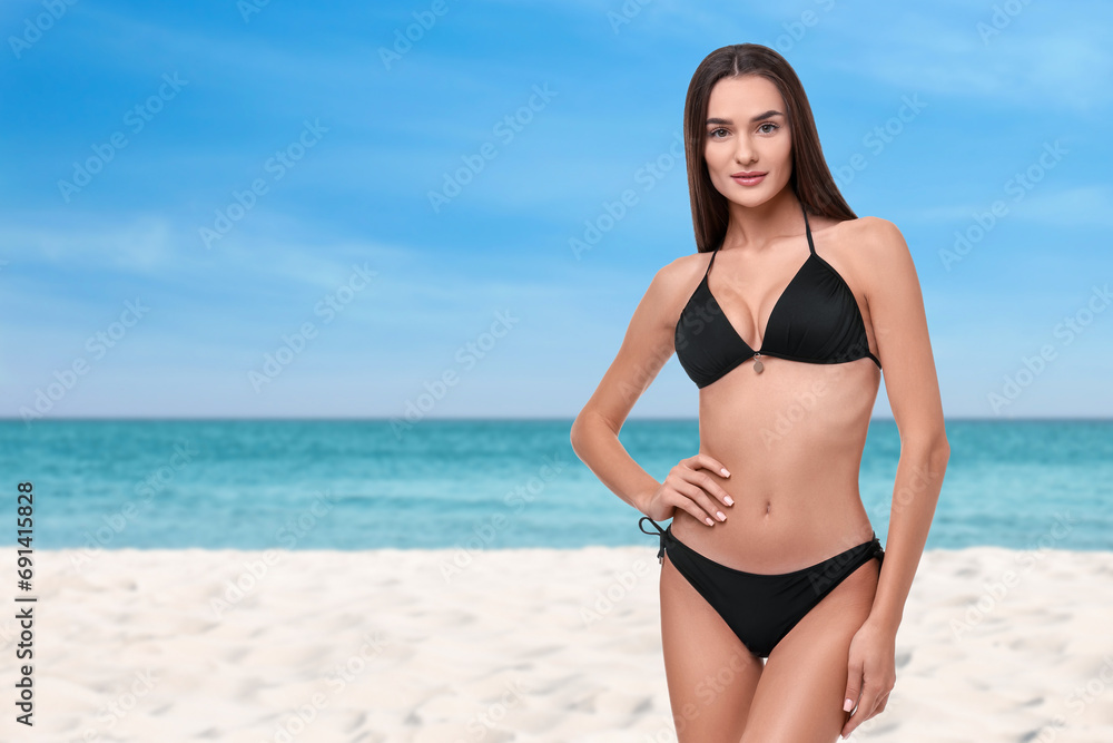 Beautiful woman in stylish black bikini on sandy beach near sea, space for text Beautiful woman in stylish black bikini on sandy beach near sea, space for text
