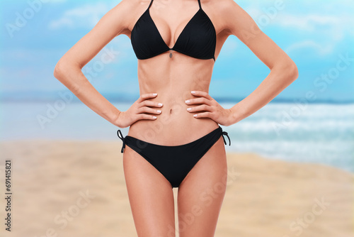 Woman in stylish black bikini on sandy beach near sea, closeup