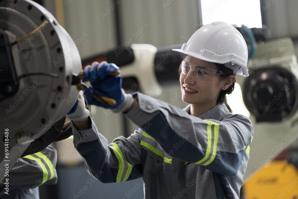 Female engineer working and checking, repair, maintenance autonomous robotics arm. Woman