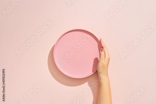 Obraz na płótnie A female hands hold a empty(blank) pink dish(plate) on pink table(desk) w salonie