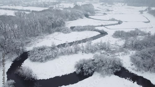 Drone flight over a river in white winter landscape with snow and ice