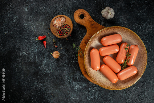 sausages on plate with herbs on a dark background. top view. copy space for text