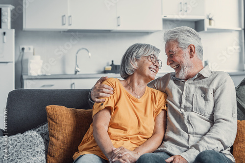 Happy mature husband and wife sit rest on couch at home hugging and cuddling, show care affection, smiling senior loving couple relax on sofa have fun, enjoy tender romantic family weekend together. photo