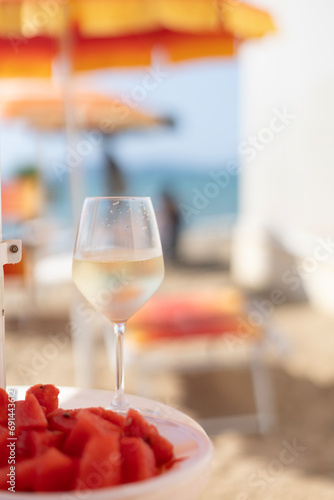 Sparkling wine with watermelon on a sunny summer day on the beach with the umbrellas and sea in the background