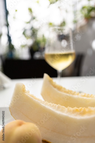 Yellow melon slices, a peach and a glass of sparkling wine on a sunny summer day