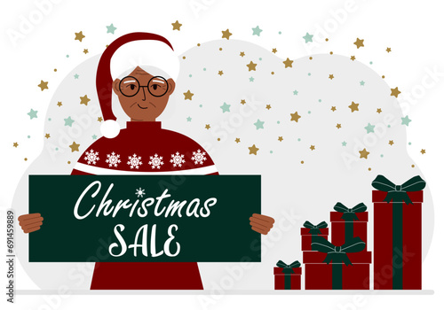 A woman in a sweater and a red Santa hat holds a poster with the text about Christmas sale in his hand.