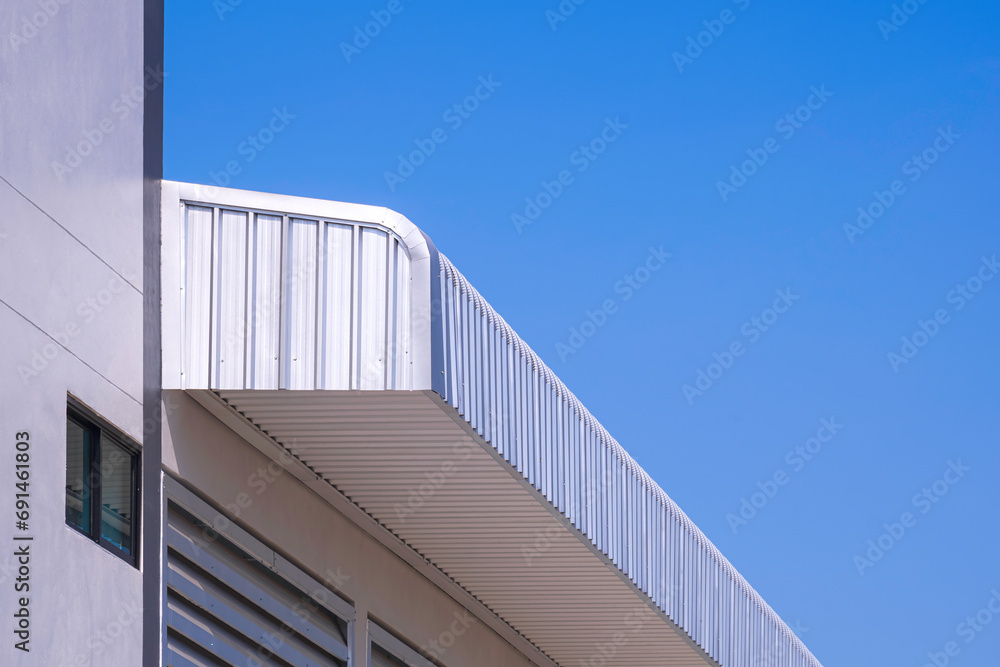 Obraz premium Aluminium steel roof eaves of new industrial building against blue clear sky background, low angle and perspective side view