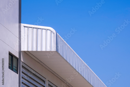 Aluminium steel roof eaves of new industrial building against blue clear sky background, low angle and perspective side view photo