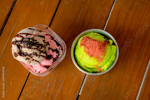 Toma cenital de dos helados uno de chocolate con fresa y otro de limón postre para el calor sobre una mesa de madera photo