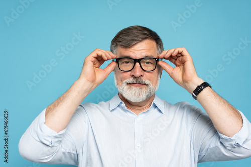 Wallpaper Mural Happy caucasian mature man trying new glasses and smiling, standing on blue background Torontodigital.ca