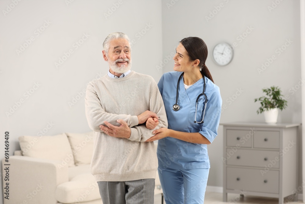 Fototapeta premium Smiling nurse supporting elderly patient in hospital