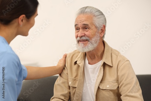 Health care and support. Nurse talking with elderly patient indoors
