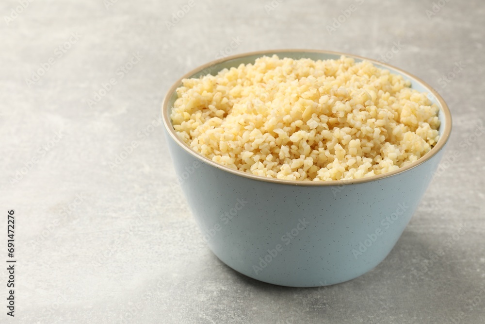 Delicious bulgur in bowl on light grey table, closeup. Space for text Delicious bulgur in bowl on light grey table, closeup. Space for text