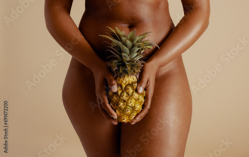Empowering female wellness: Sensual woman holding a pineapple in a studio photo