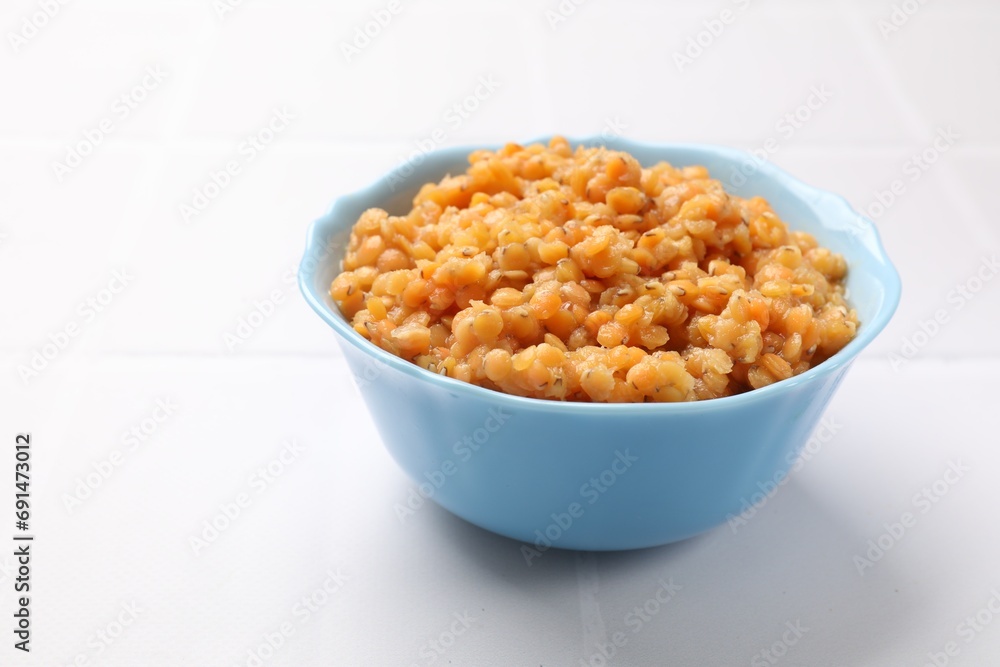 Delicious red lentils in bowl on white table, closeup. Space for text Delicious red lentils in bowl on white table, closeup. Space for text