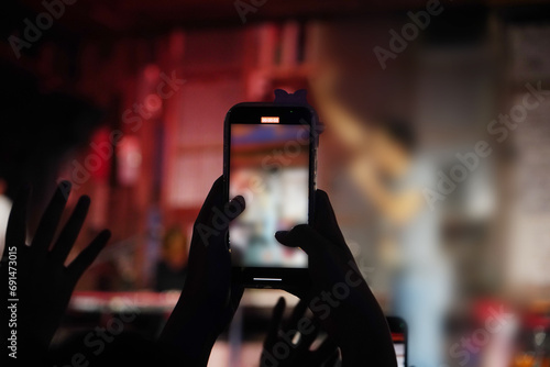 Person holding smartphone with background of concert