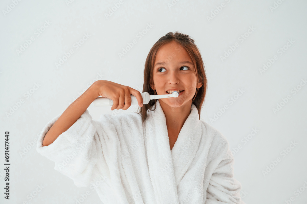 Using the toothbrush. Conception of beauty and self care. Young girl is in the studio Using the toothbrush. Conception of beauty and self care. Young girl is in the studio