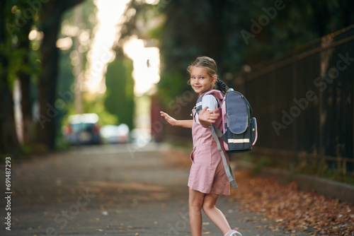 Schoolgirl with backpack is outdoors